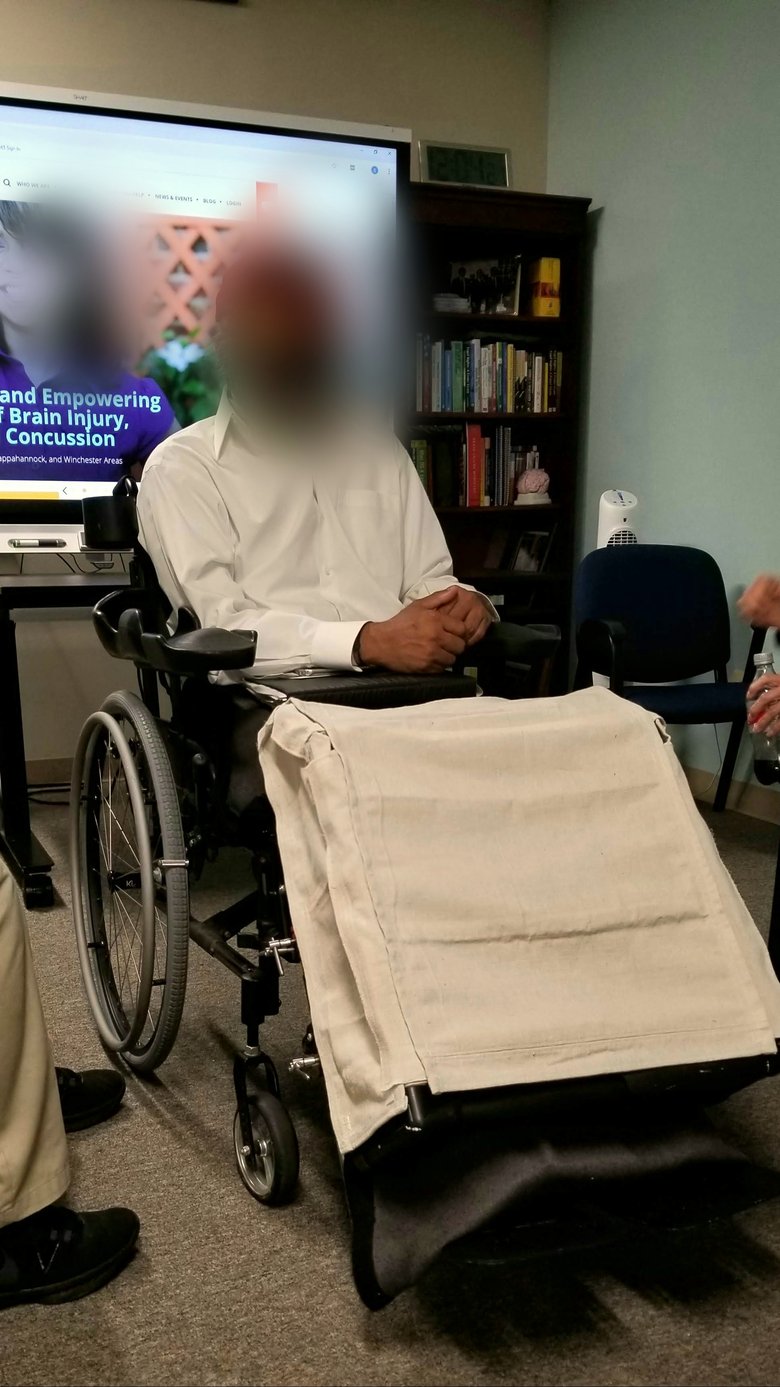Former client using the finished leg-protector mounted to the front of his power wheelchair, several months after delivery. Subject's face anonymized. He reported the device gave him more confidence leaving the house.